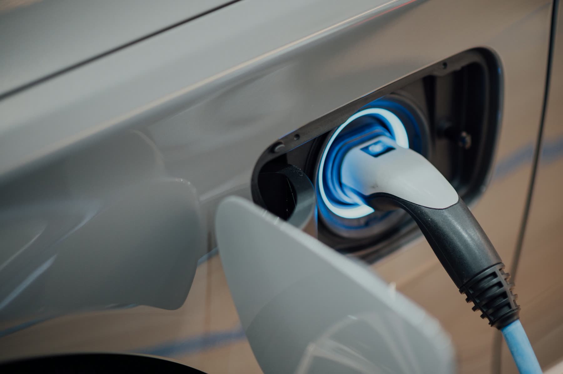 Wall-mounted electric vehicle charger on a pale rendered wall