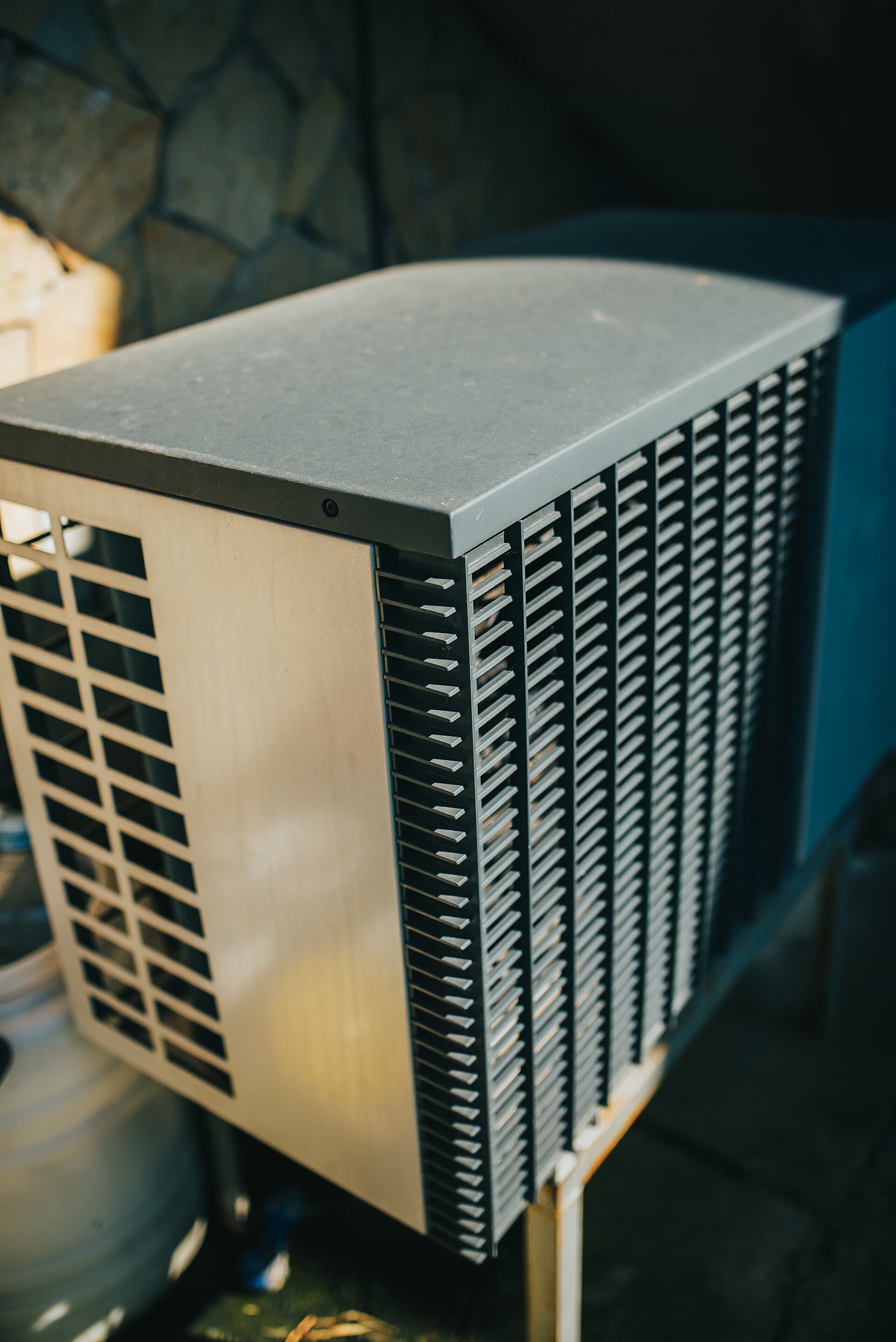 Outdoor heat-pump unit installed beside the wall of a brick home
